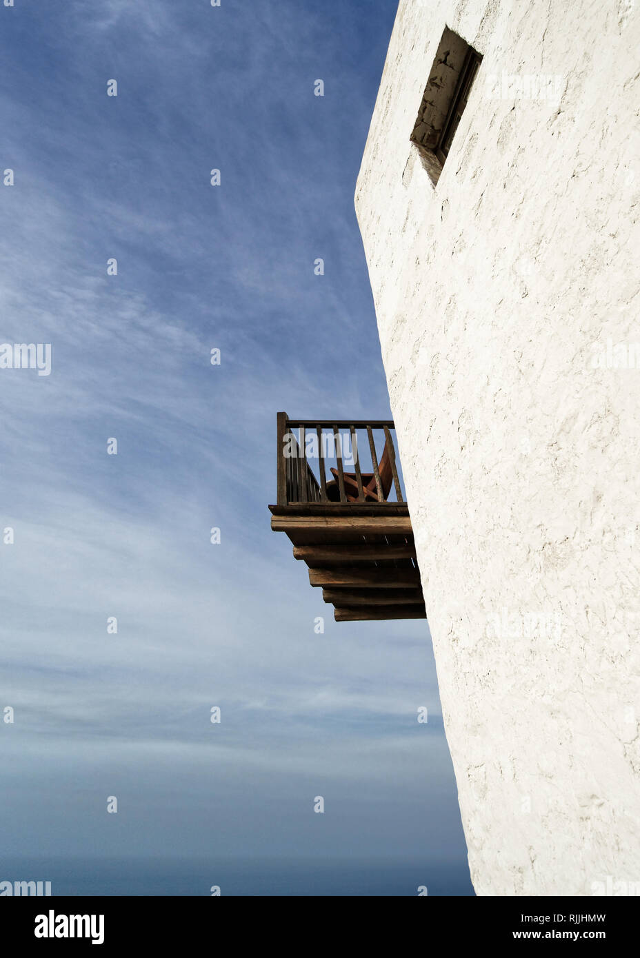 Vista prospettica dal basso di un vecchio bianco edificio tipico con un balcone in legno e una finestra in background l'oceano e cielo blu - Ubicazione Foto Stock