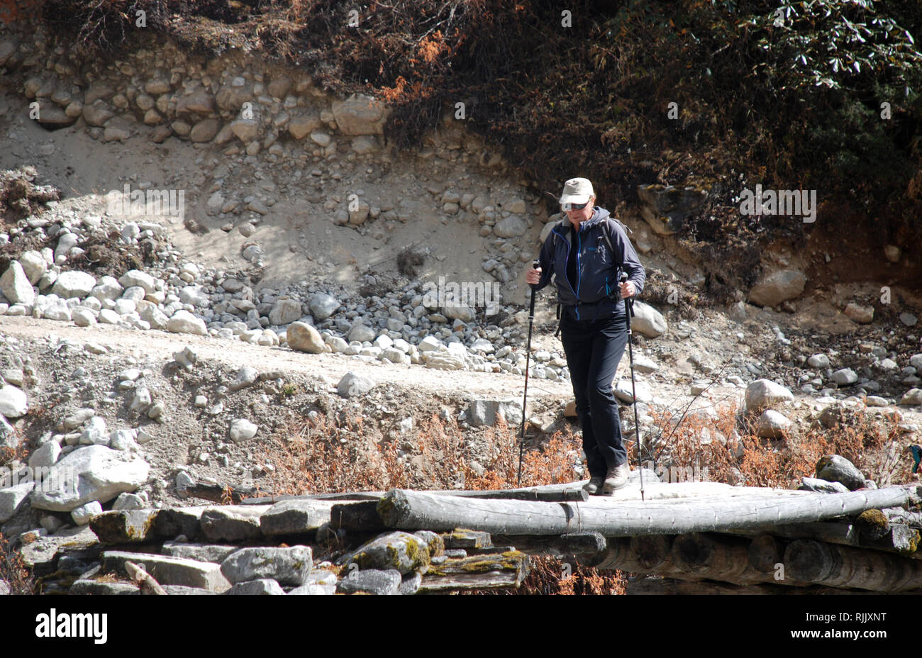 Un escursionista attraversa un piccolo ponte sopra il fiume Tamur nel Nepal orientale Foto Stock