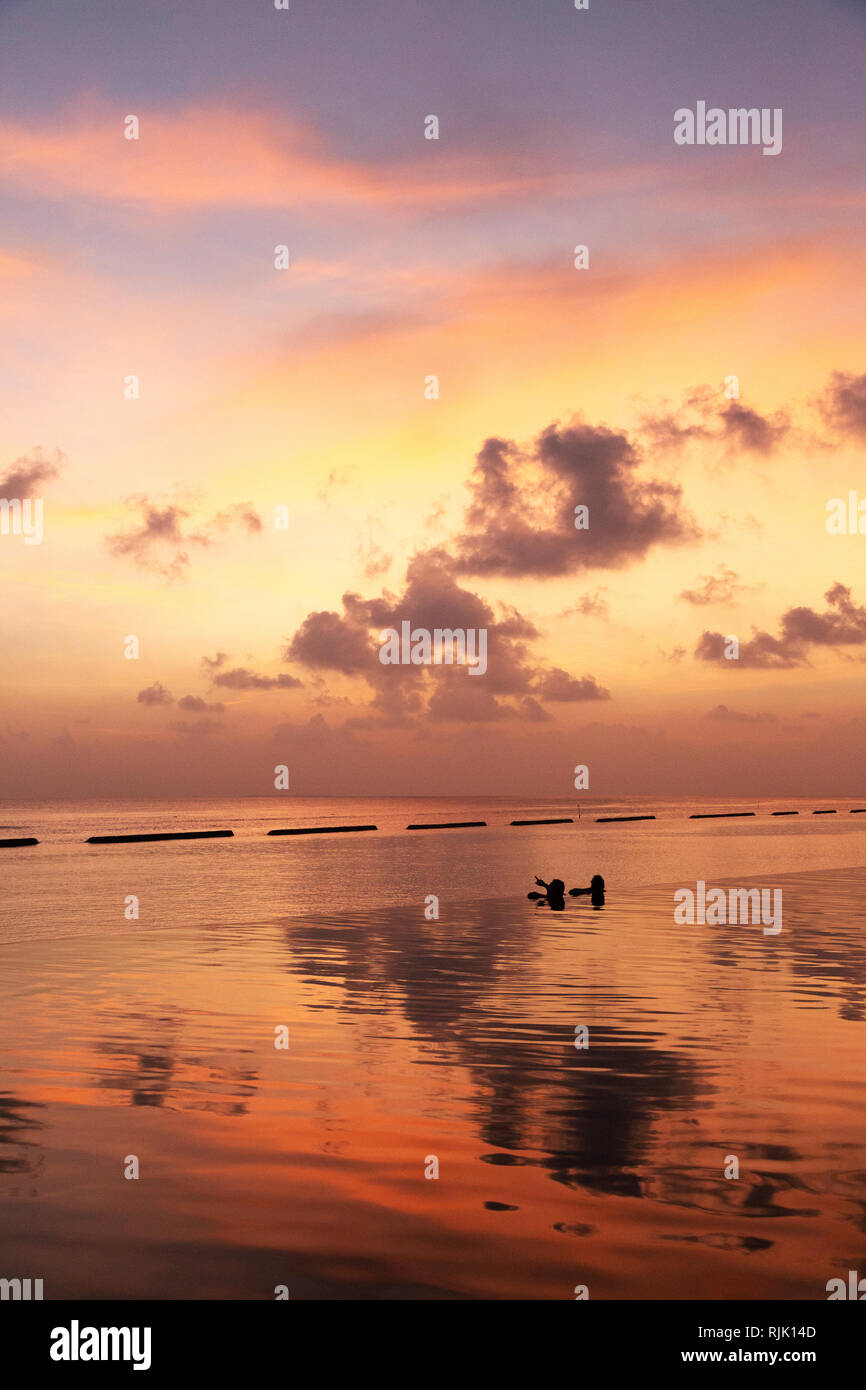 Maldive viaggio - un paio di guardare un drammatico tramonto colorato su Rasdhoo atoll, Maldive, Asia Foto Stock