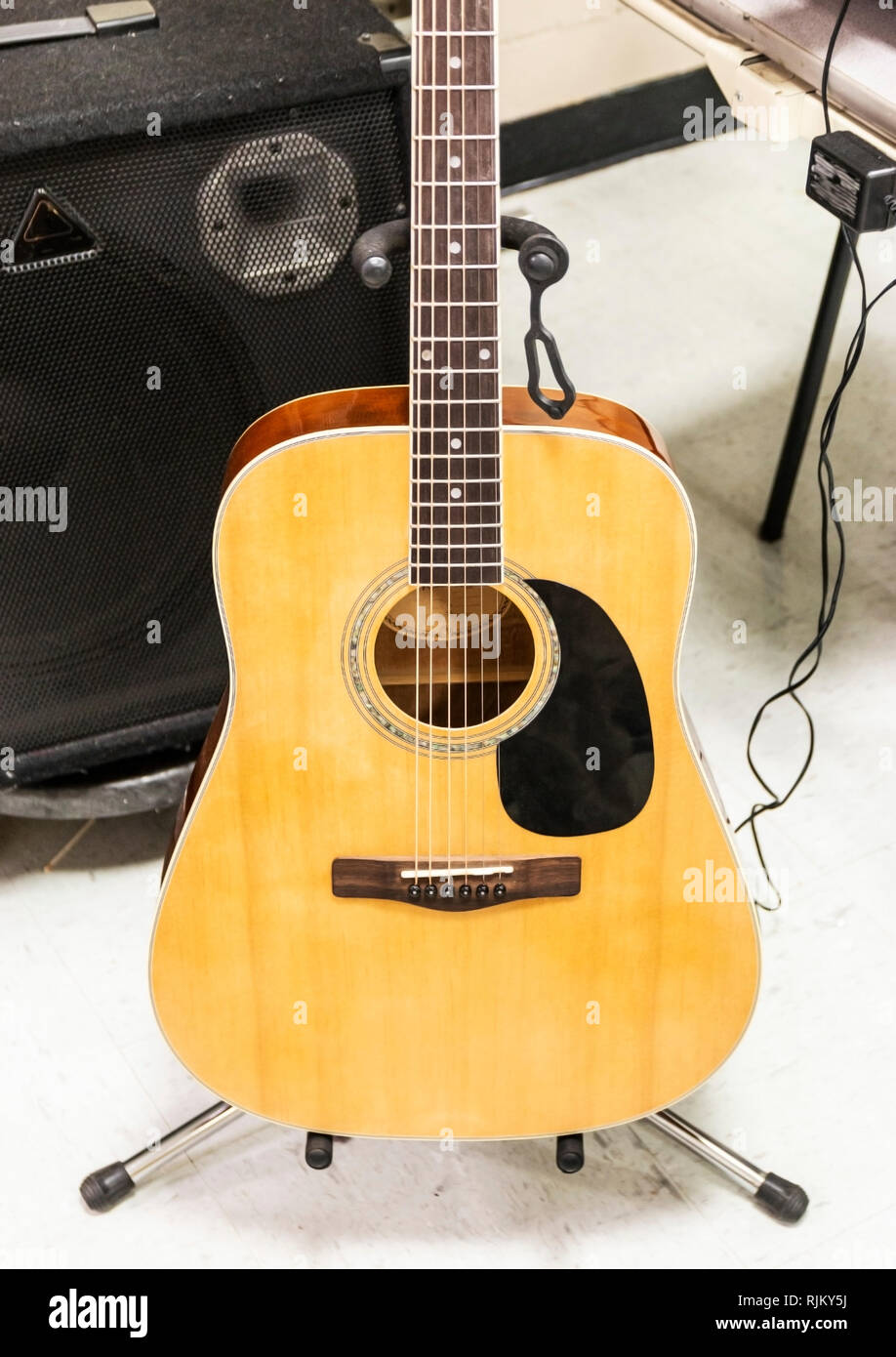 Una chitarra acustica è eretta su una medaglia stand nero con un altoparlante dietro è pronto per essere riprodotto. Foto Stock