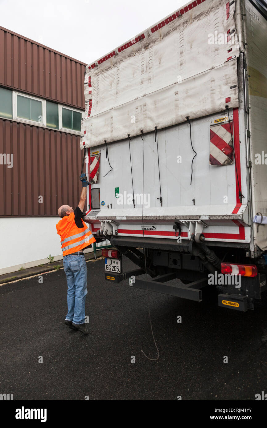 Automobilista dopo le operazioni di carico e scarico controlla i documenti di trasporto Foto Stock