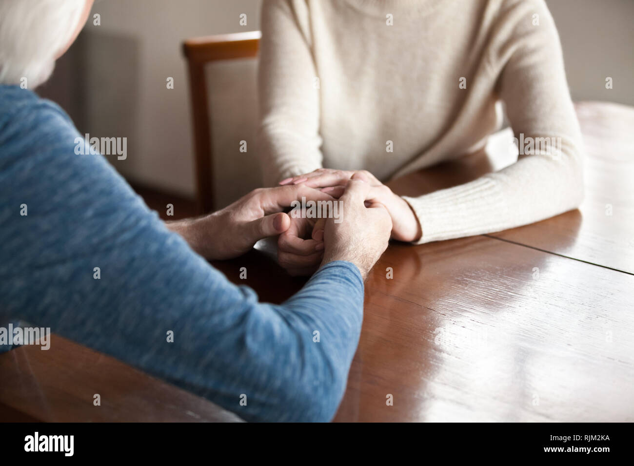 Persone di età matura in amore seduta a tavola tenendo le mani Foto Stock