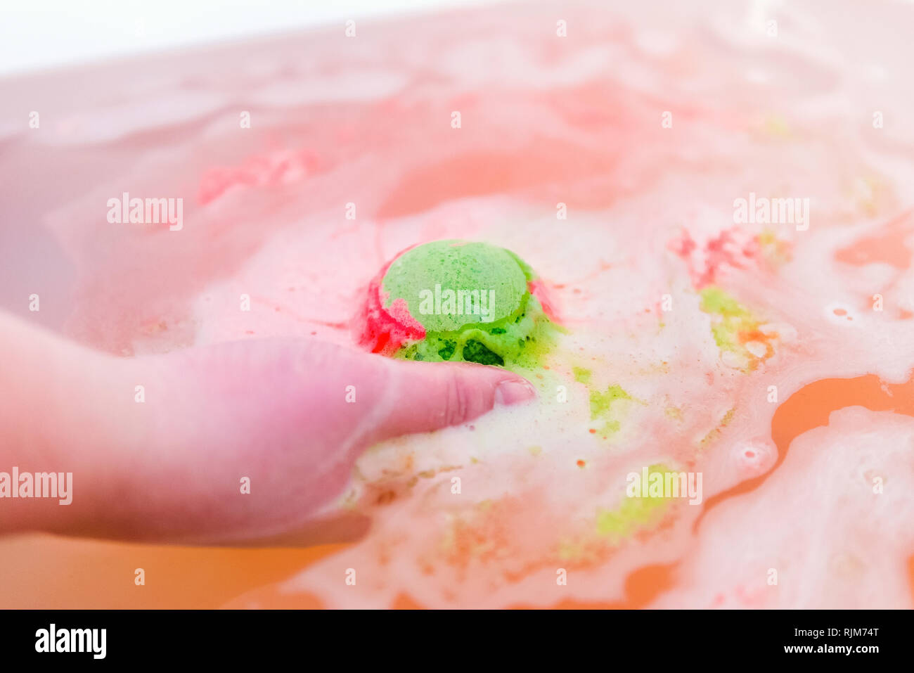 Il verde e il rosso sfera di gorgogliamento di sali da bagno in mani. Bomba  per la vasca da bagno. Si scioglie in mani Foto stock - Alamy