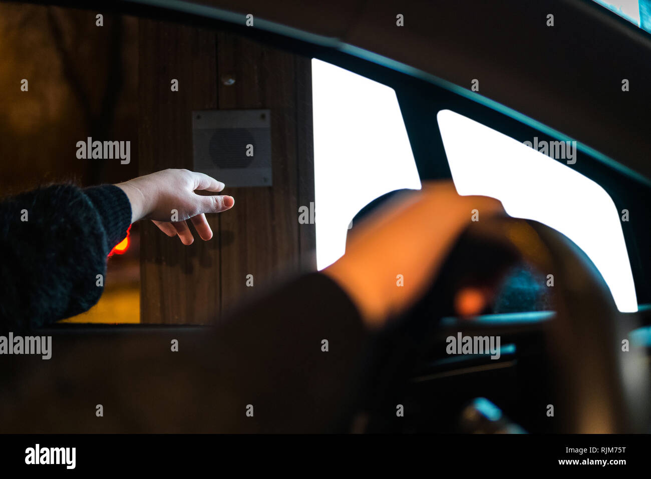 Donna canto di raggiungere il pulsante di azionamento attraverso per ordinare il fast food. Uomo al sedile di guida ordinazione presso il ristorante Foto Stock