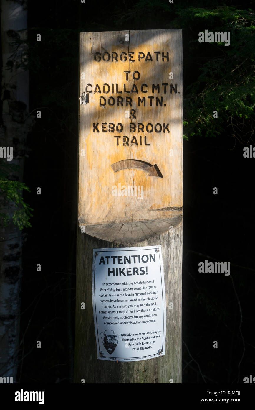 In legno intagliato segno per sentieri per escursioni nel Parco Nazionale di Acadia, Maine, Stati Uniti d'America. Un avviso per gli escursionisti dal National Park Service è avvitato al posto di legno. Foto Stock