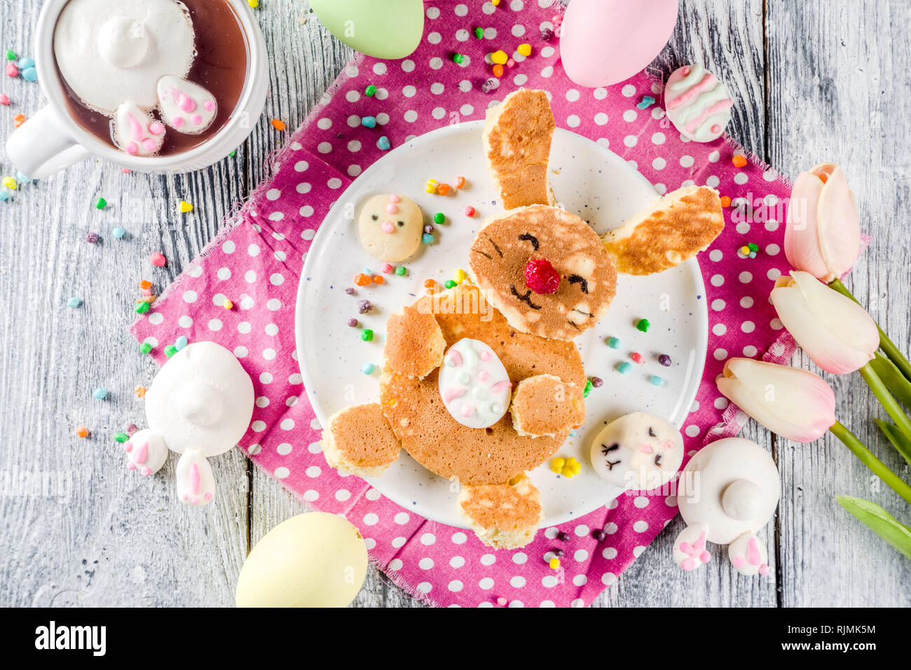 Funny colazione di pasqua cibo, kids pancake in forma di bunny coniglio, con cioccolata calda, vista dall'alto lo sfondo di legno spazio copia Foto Stock