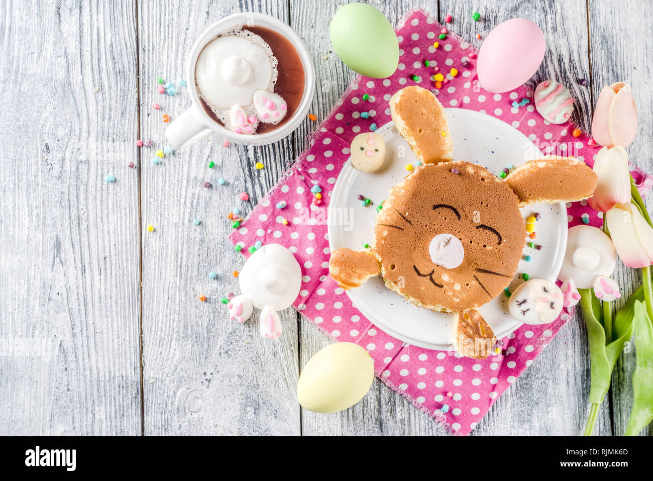 Funny colazione di pasqua cibo, kids pancake in forma di bunny coniglio, con cioccolata calda, vista dall'alto lo sfondo di legno spazio copia Foto Stock