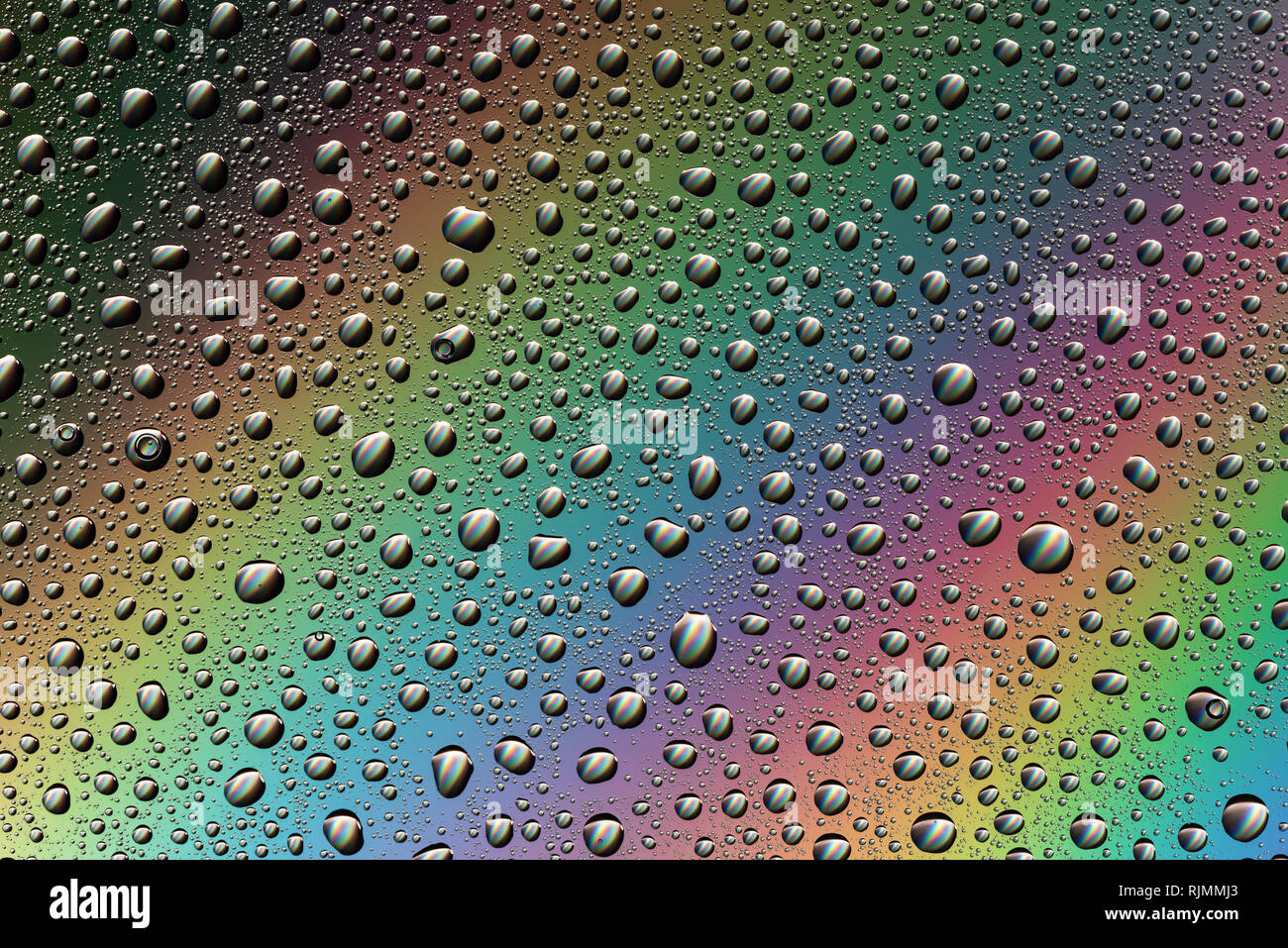 Gocce di acqua sul vetro nella luce dell'arcobaleno. Astrazione. Sfondo. Foto Stock