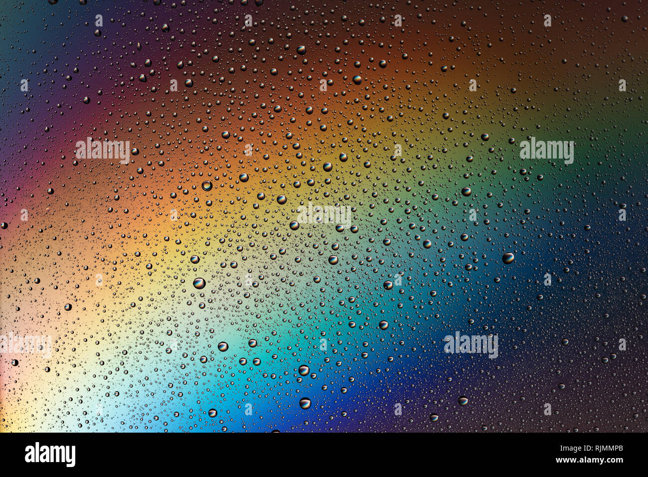 Gocce di acqua sul vetro nella luce dell'arcobaleno. Astrazione. Sfondo. Foto Stock