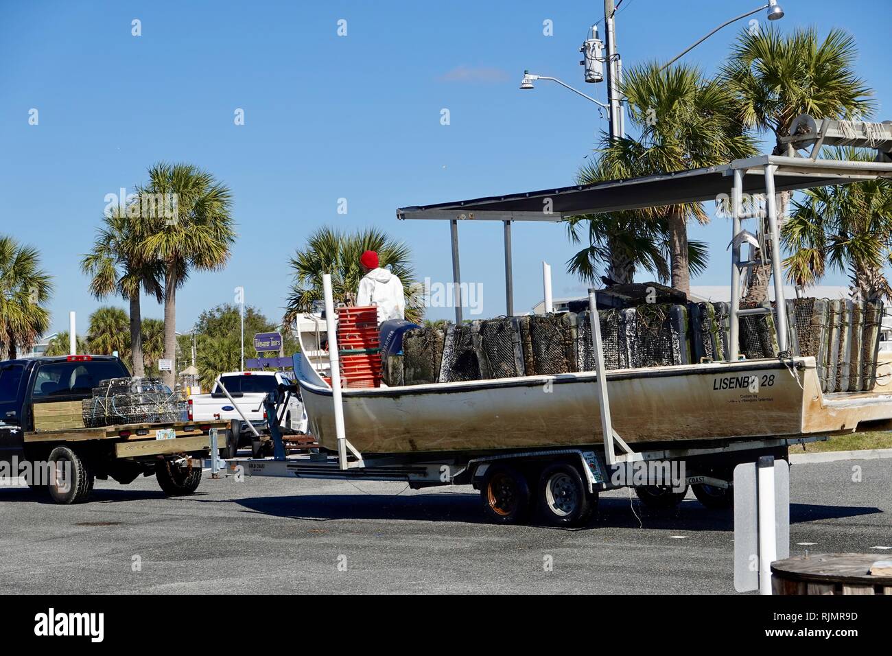 Clamming barca sul rimorchio con un pescatore in fronte e pile di sacchetti di molluschi/ceste, Cedar Key, Florida, Stati Uniti d'America Foto Stock