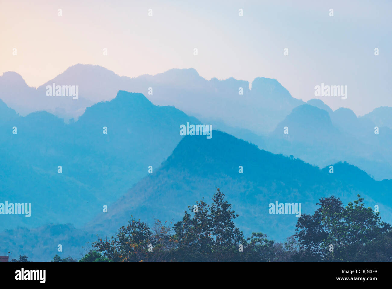 Arancio e giallo tramonto con le montagne sagome. Gradiente di natura vivace sfondo Foto Stock