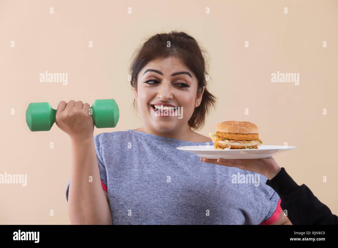 Excited donna sovrappeso esercizio ritagliate dando mano Burger Foto Stock