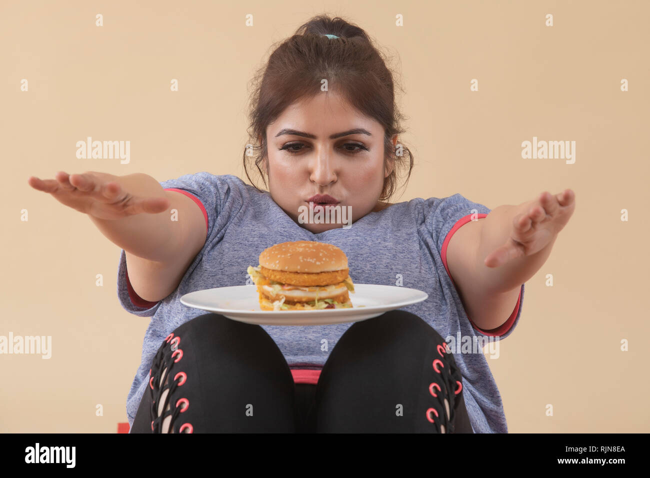 Donna sovrappeso esercitando con Burger Foto Stock