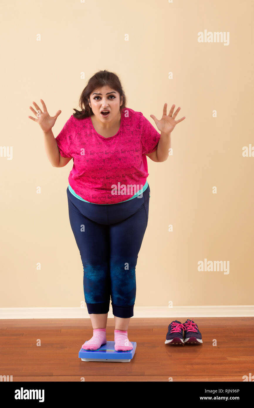 Scioccato sovrappeso donna in piedi sulla scala di misurazione Foto Stock