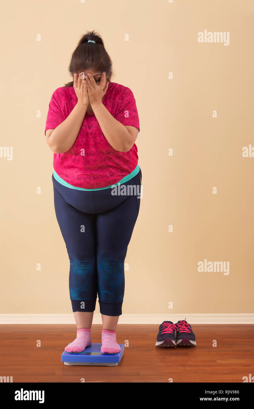 Scioccato sovrappeso donna in piedi sulla scala di misurazione Foto Stock