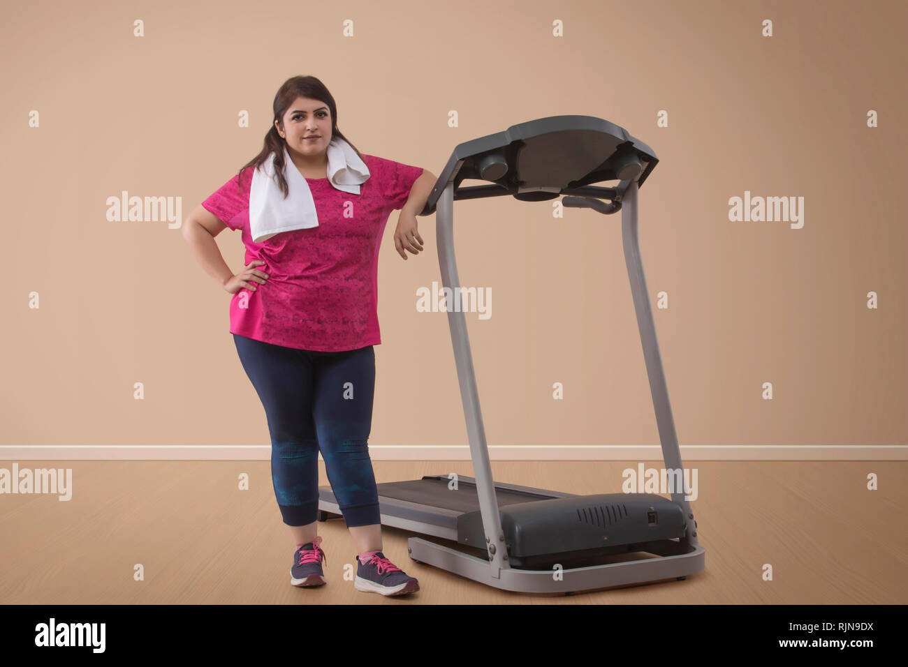 Ritratto di donna sovrappeso in piedi con tapis roulant Foto Stock