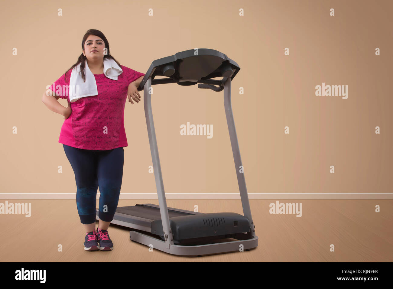Ritratto di donna sovrappeso in piedi con tapis roulant Foto Stock