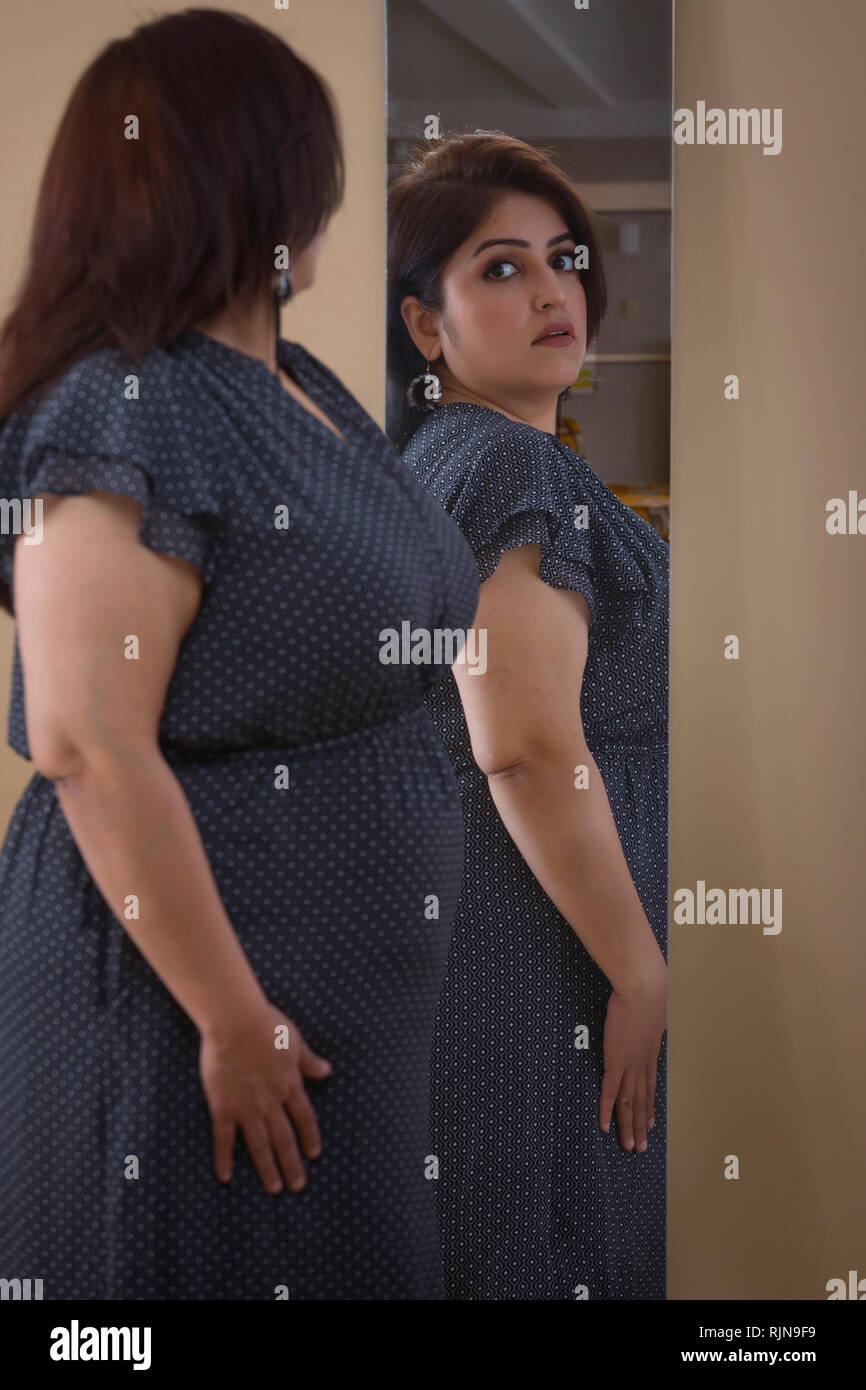 Donna obesa cercando abito in cerca dello specchio Foto Stock