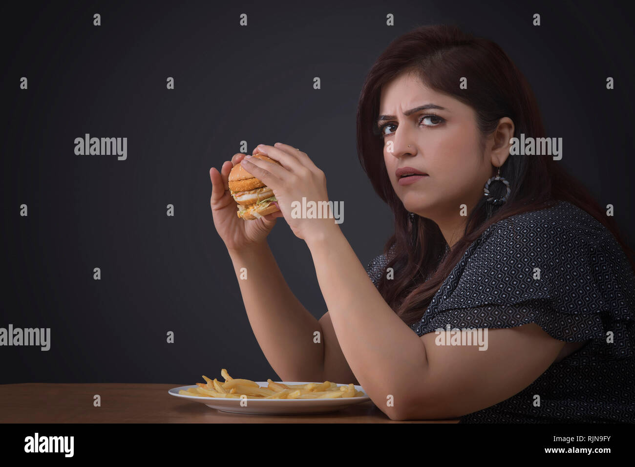 Arrabbiato donna grassa mangiare un hamburger Foto Stock