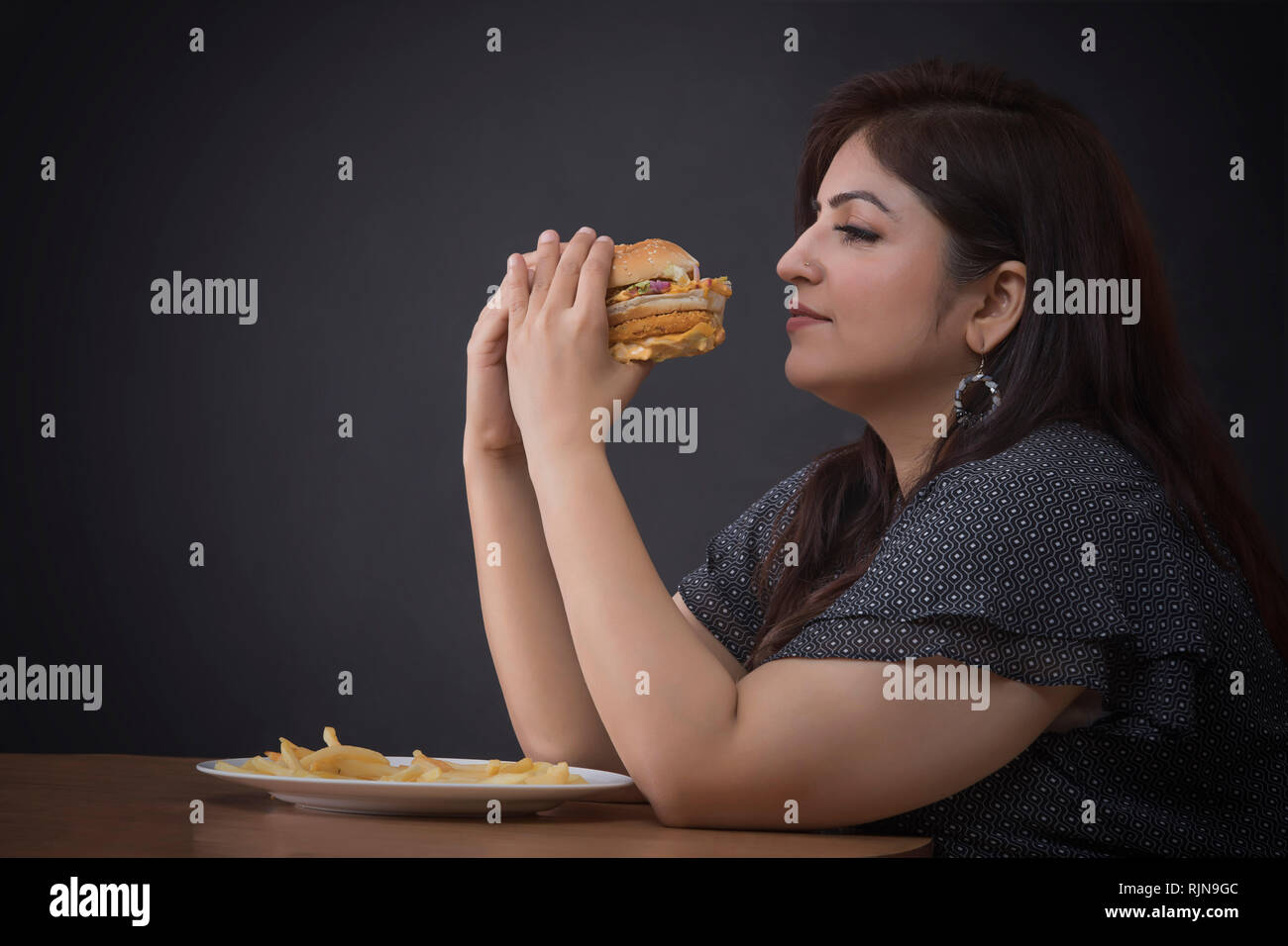 Donna grassa mangiare un hamburger Foto Stock