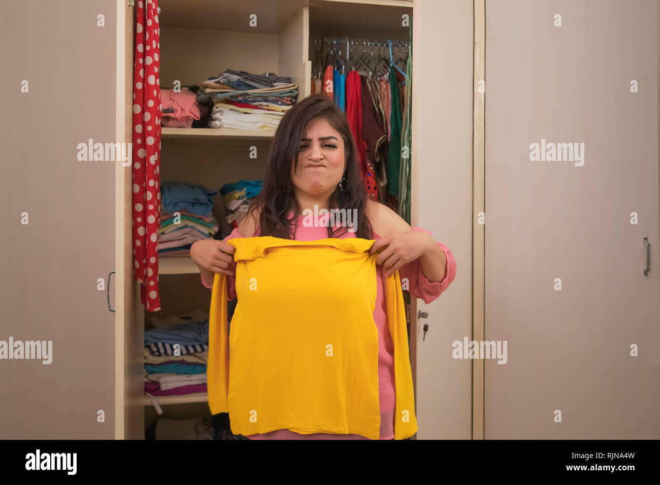 Arrabbiato donna grassa cercando di usura di piccole dimensioni di giallo t-shirt Foto Stock