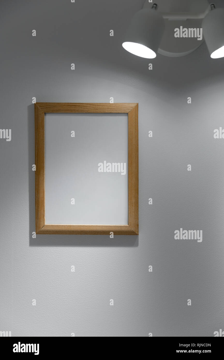 Legno bianco cornice immagine appesa sulla parete sotto la luce Foto Stock