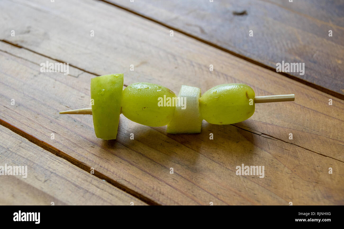 Frutta fresca pezzi su uno spiedino su un tavolo in legno immagine superiore in formato paesaggio con spazio di copia Foto Stock