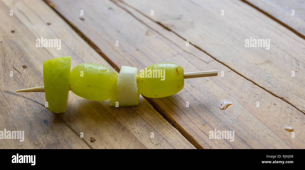 Frutta fresca pezzi su uno spiedino su un tavolo in legno immagine superiore in formato paesaggio con spazio di copia Foto Stock