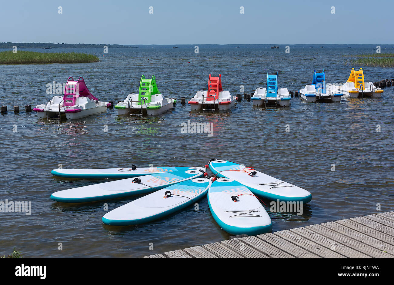 Scheda per Stand Up Paddle Surf Sup e colorate barche a pedali con acqua scorre sulla superficie dell'acqua del lago. Giornata di sole. Foto Stock