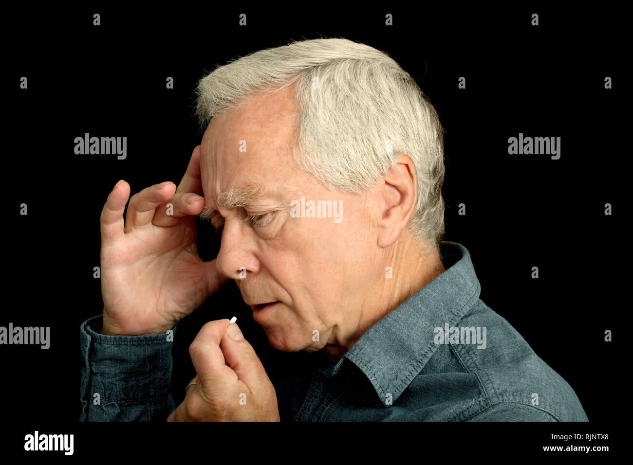 Un pelo grigio l uomo nella sua anni sessanta di prendere una compressa Foto Stock