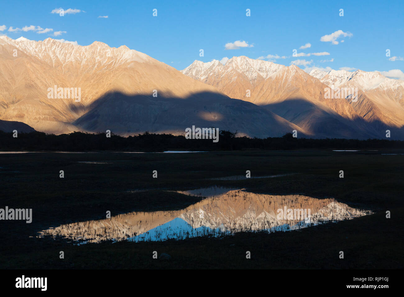 Paesaggio con leggermente innevate montagne che si riflettono nell'acqua, area di Hunder, Valle di Nubra, Ladakh, Jammu e Kashmir India Foto Stock
