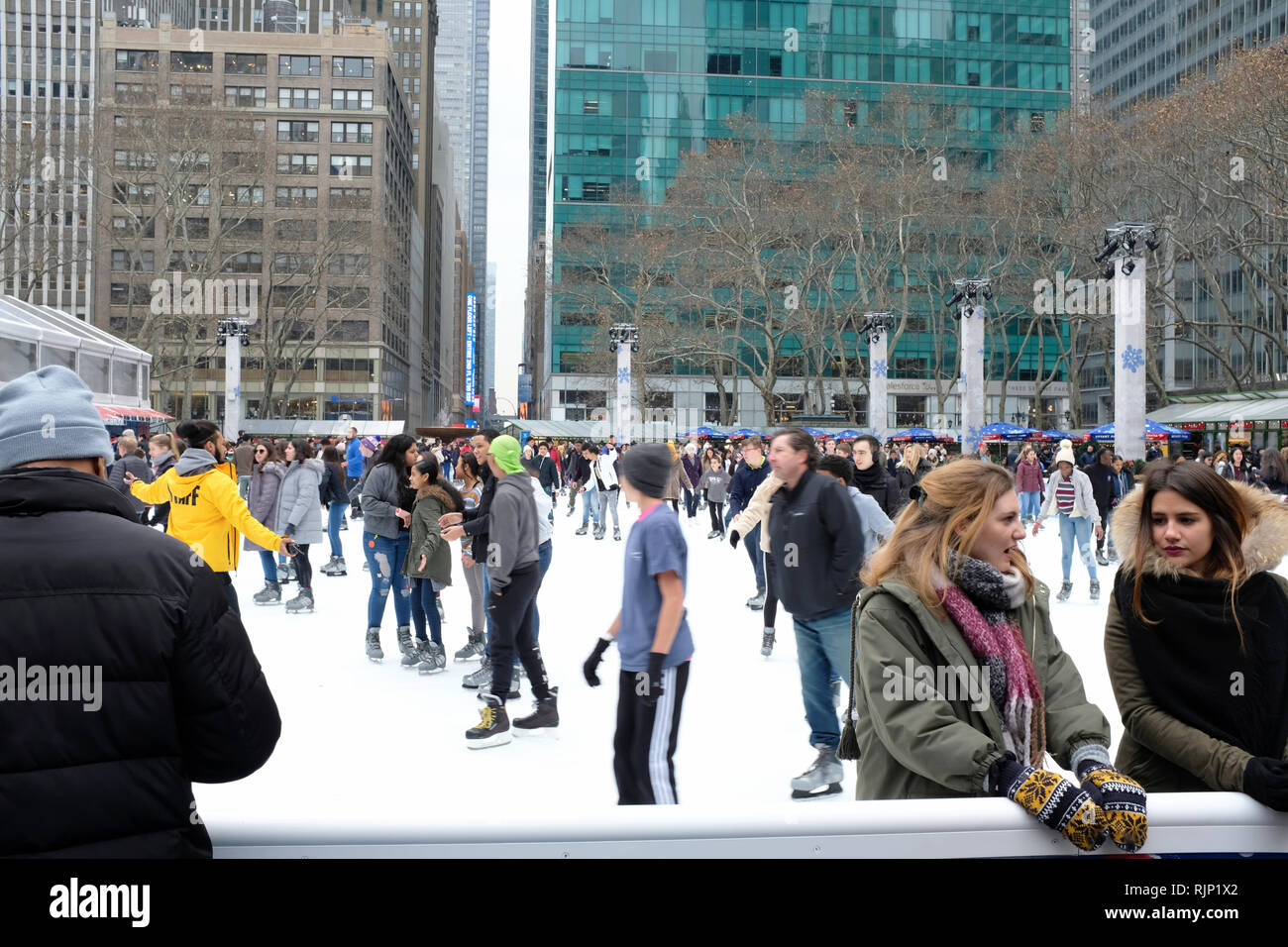 La gente di pattinaggio a Bryant Park durante la stagione delle feste con torri di uffici nel centro di Manhattan in background. New York City.NY.USA Foto Stock