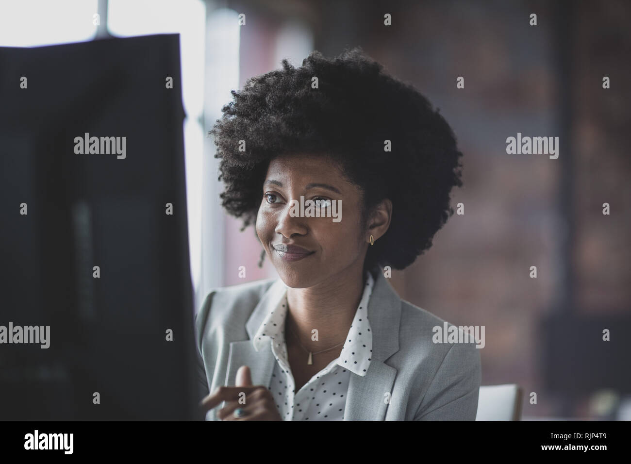 Femmina African American business executive lavora in un ufficio su un computer desktop Foto Stock