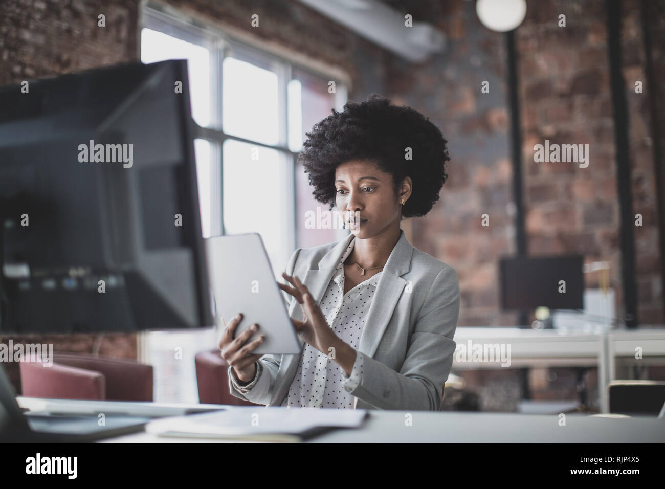 Femmina African American business executive lavora in un ufficio su una tavoletta digitale Foto Stock
