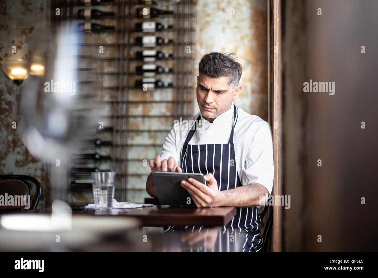 Lo chef maschio lavora su tavoletta digitale nel ristorante Foto Stock