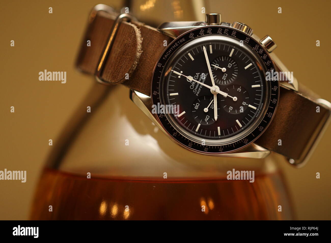 Omega Speedmaster watch sul cuoio cinturino nato avvolto intorno a una  bottiglia di single malt Scotch su sfondo marrone Foto stock - Alamy