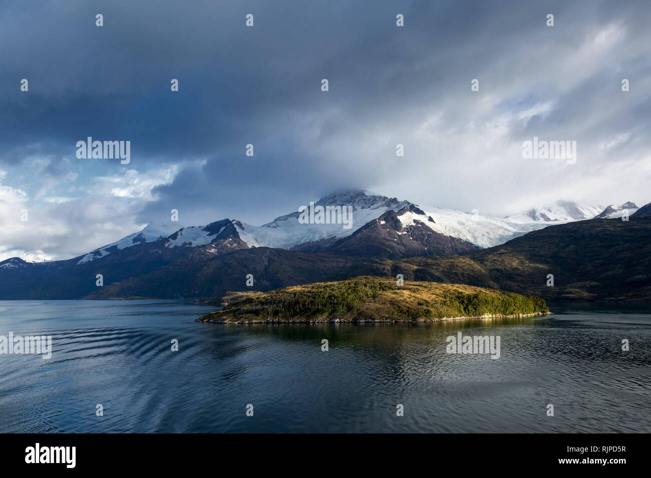 Un'isola soleggiata di fronte alla montagna di Darwin, visto da una nave di crociera in Vicolo del ghiacciaio, Ushuaia, Argentina, preso poco dopo l'alba. Foto Stock
