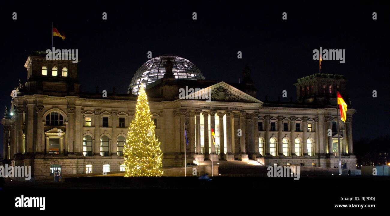 Una fotografia presa dell'esterno dell'Edificio del Reichstag, un edificio storico di Berlino, Germania, costruito per alloggiare la Dieta Imperiale dell'impero tedesco. Un grande albero di Natale si illumina il cielo di notte. Foto Stock