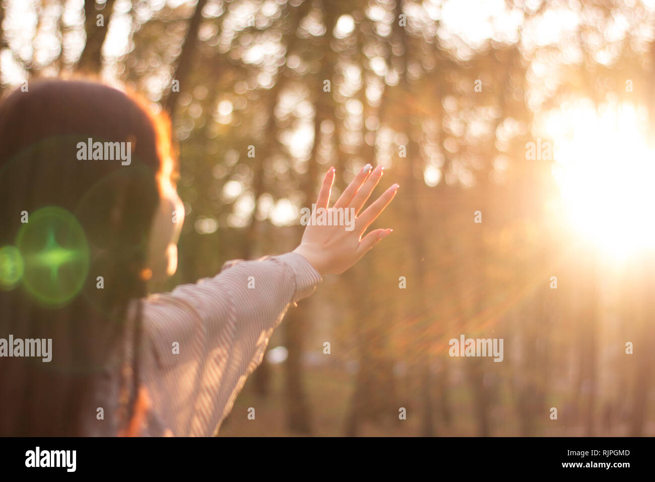 La ragazza si chiude una mano la luce solare che passa attraverso le sue dita su un lato Foto Stock