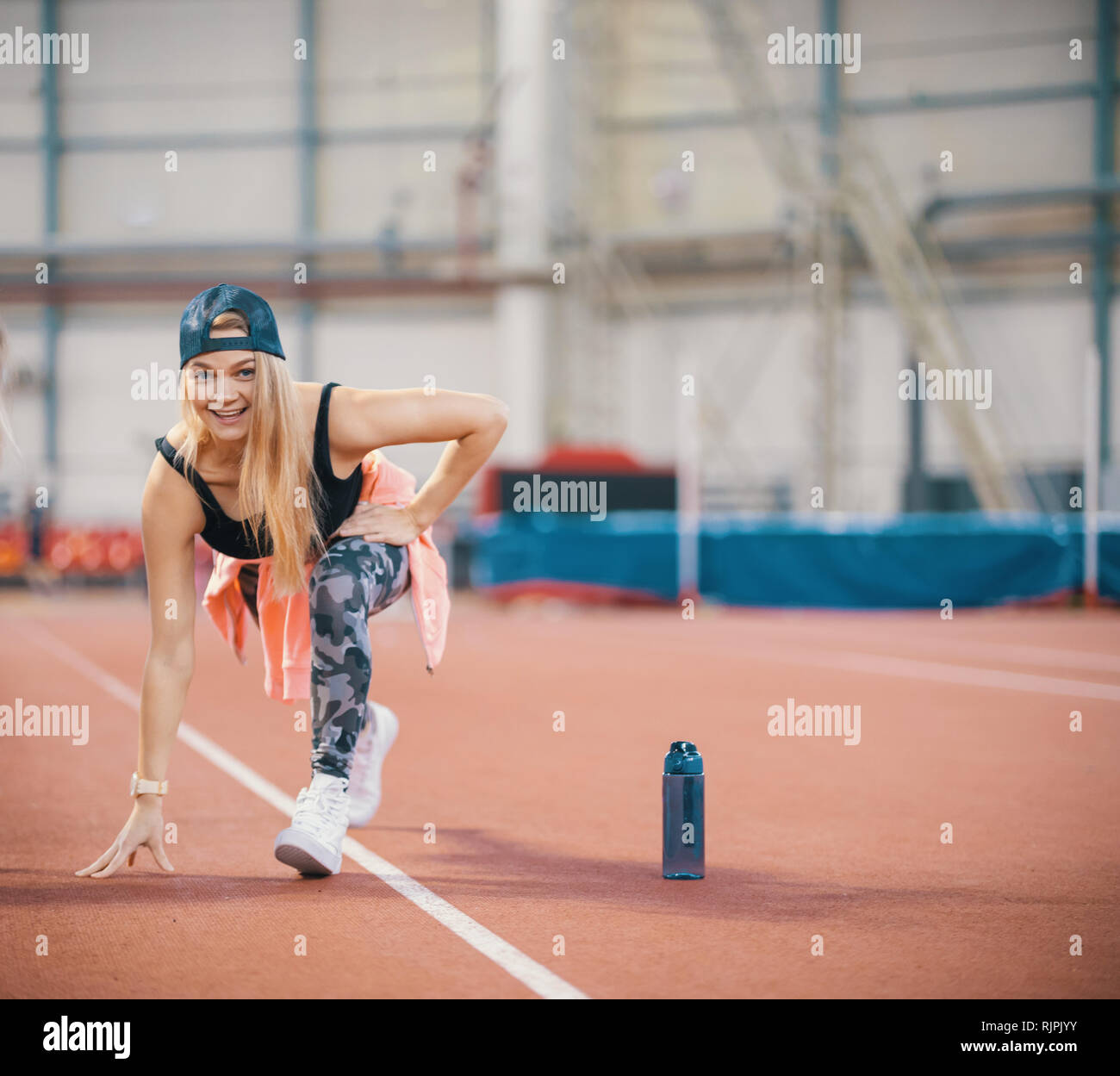 Montare la giovane donna di atletica in fase di riscaldamento. Guardando nella telecamera Foto Stock