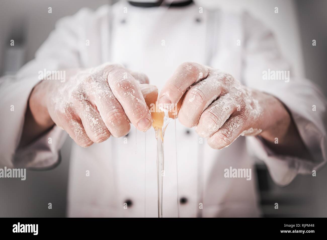 Cucina caucasica Chef nella sua 30s di cracking e aggiunta di uovo alla crosta di pane. Industria da pranzo. Foto Stock