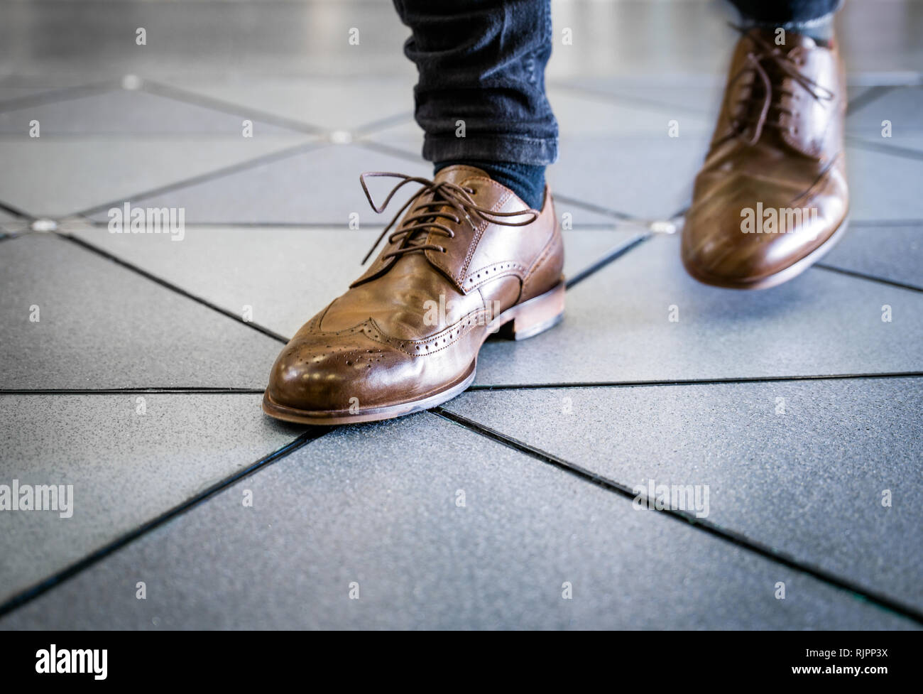 Piedi in coppia di brogues sul pavimento piastrellato Foto Stock