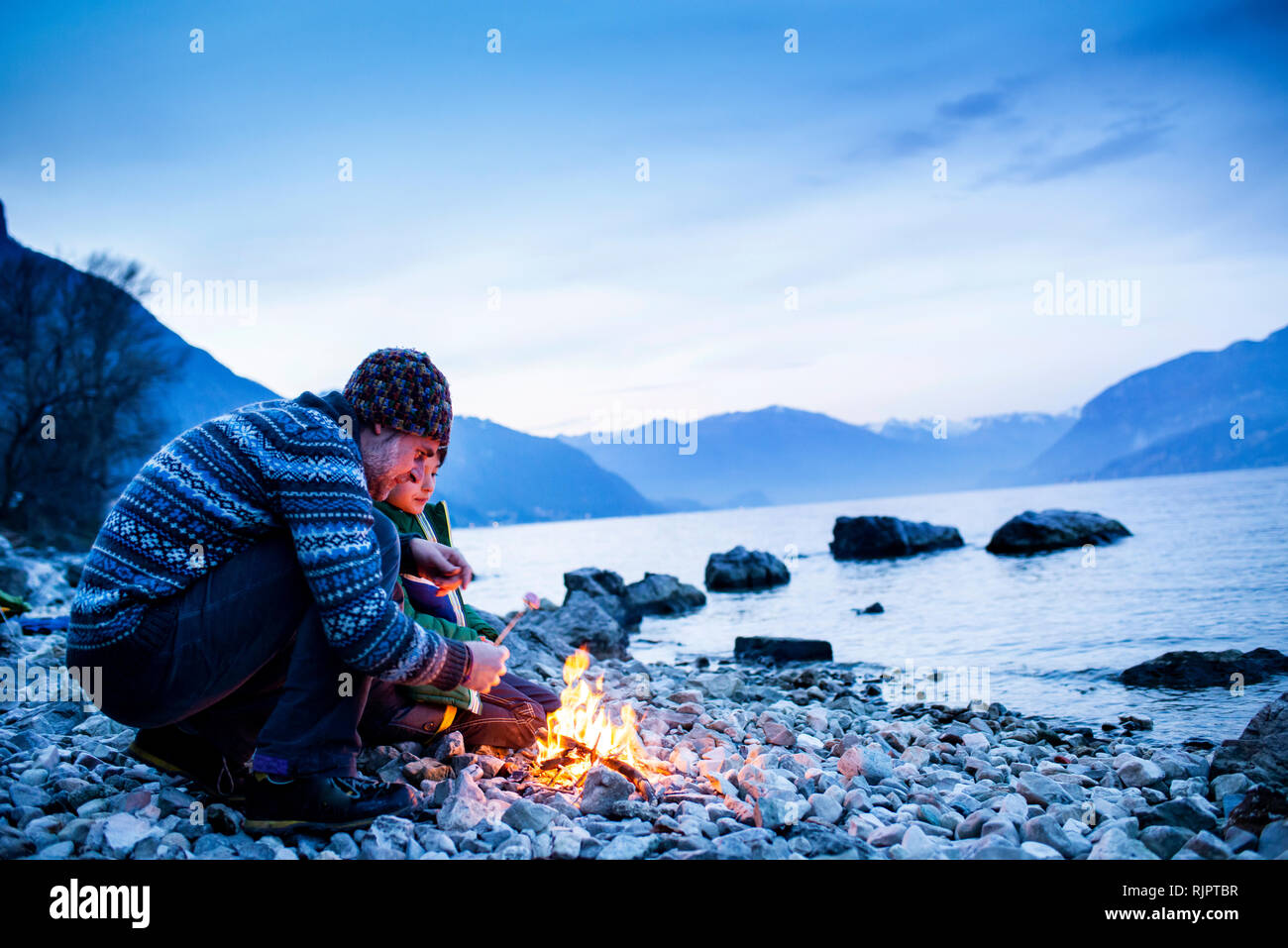 Padre e figlio la tostatura marshmallows oltre il falò, Onno, Lombardia, Italia Foto Stock