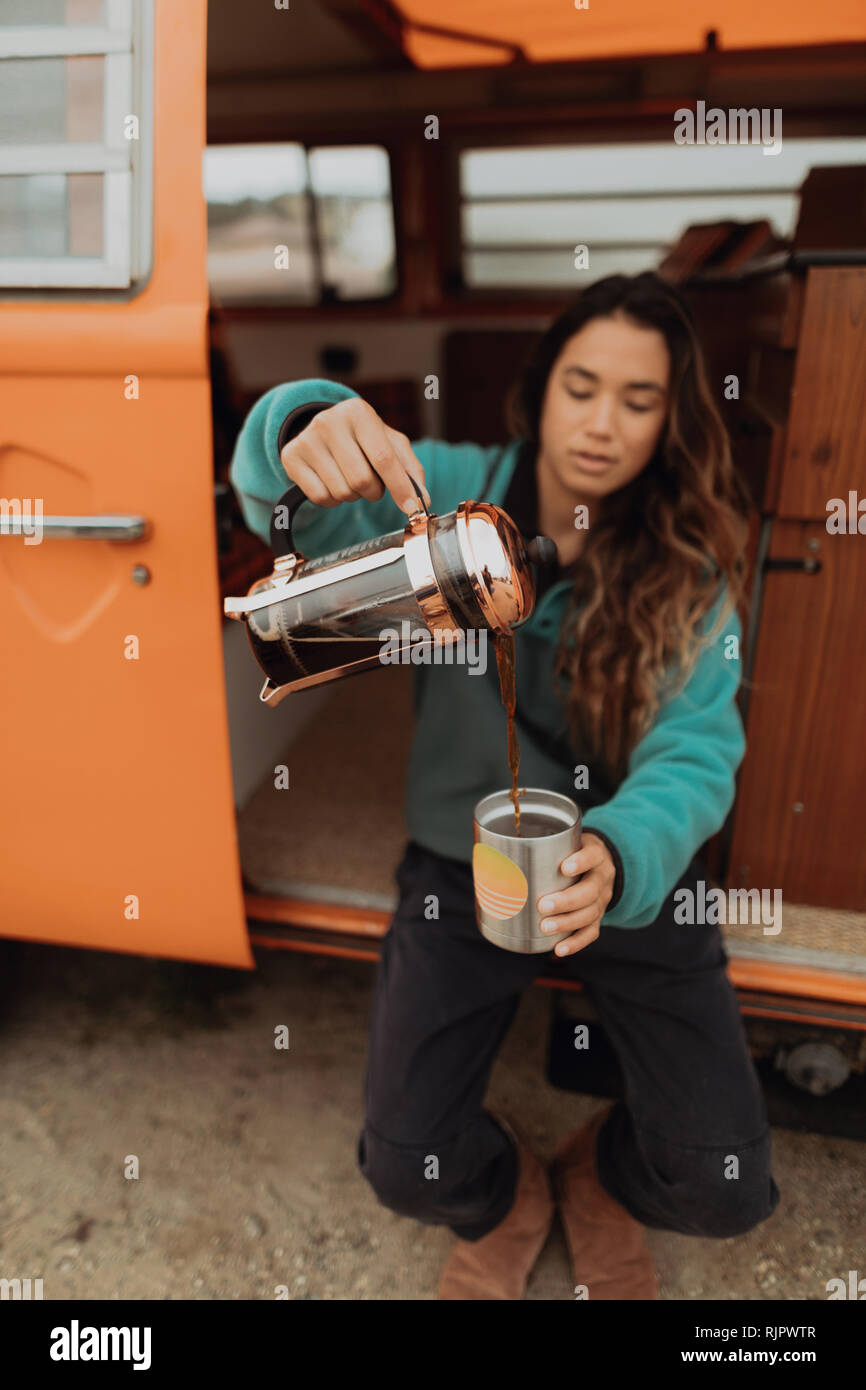 Giovane donna versando il caffè da veicolo per attività ricreative, Jalama, CALIFORNIA, STATI UNITI D'AMERICA Foto Stock