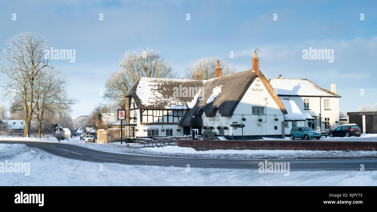 Il Pub Red Lion nella neve in Avebury, Wiltshire, Inghilterra. Vista panoramica Foto Stock
