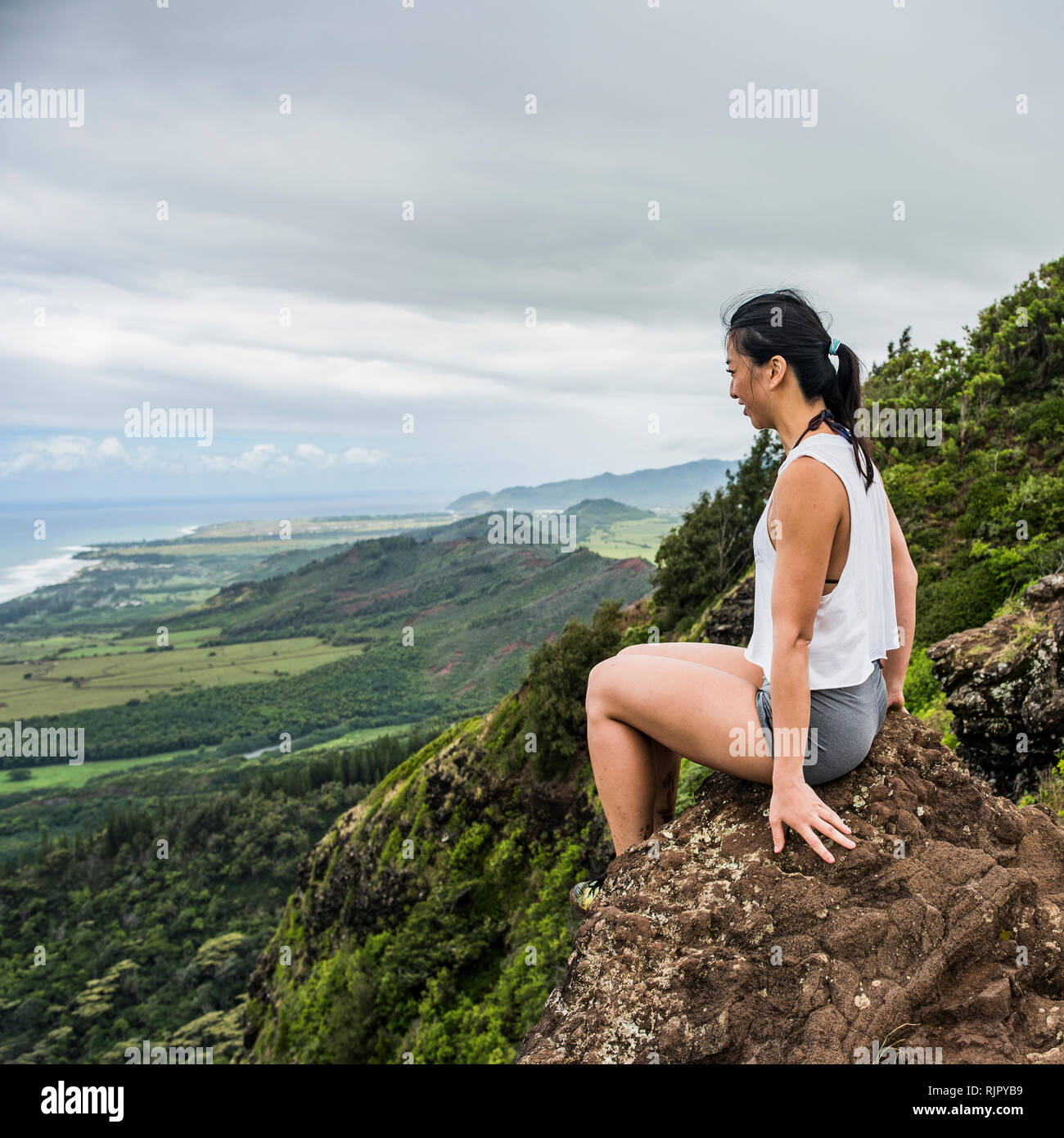 Escursionista su roccia sulla cima della montagna, Sleeping Giant Trail, Kauai, Hawaii Foto Stock