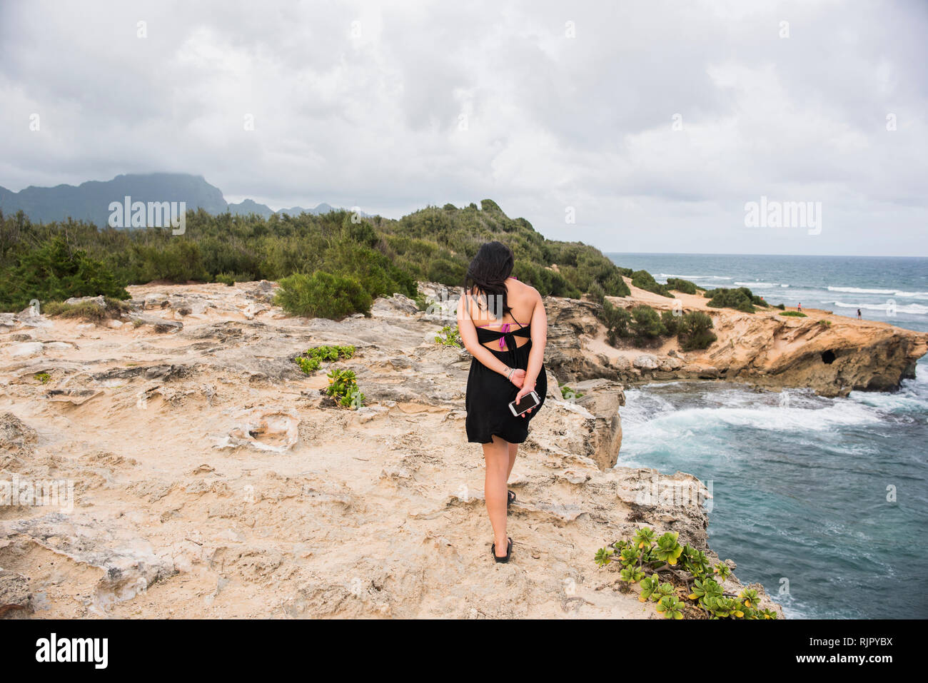 Donna che cammina con il cellulare in mano, Shipwreck, Kauai, Hawaii Foto Stock