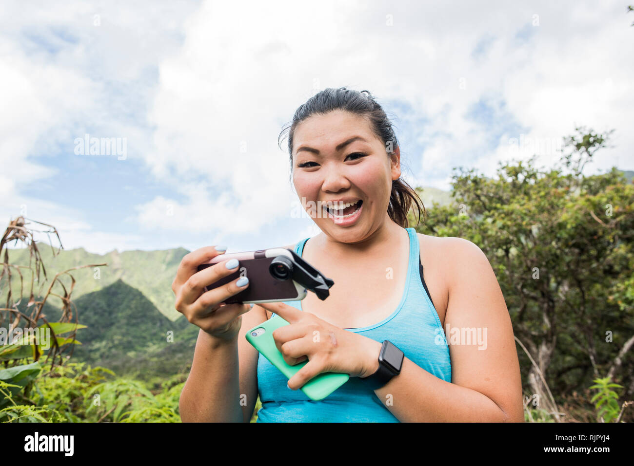 Escursionista con telefoni cellulari nella foresta pluviale, Iao Valley, Maui, Hawaii Foto Stock