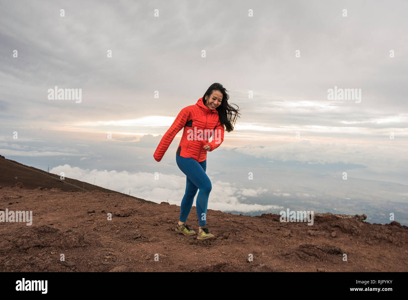 Donna che cammina lungo il bordo della montagna, Haleakala National Park, Maui, Hawaii Foto Stock