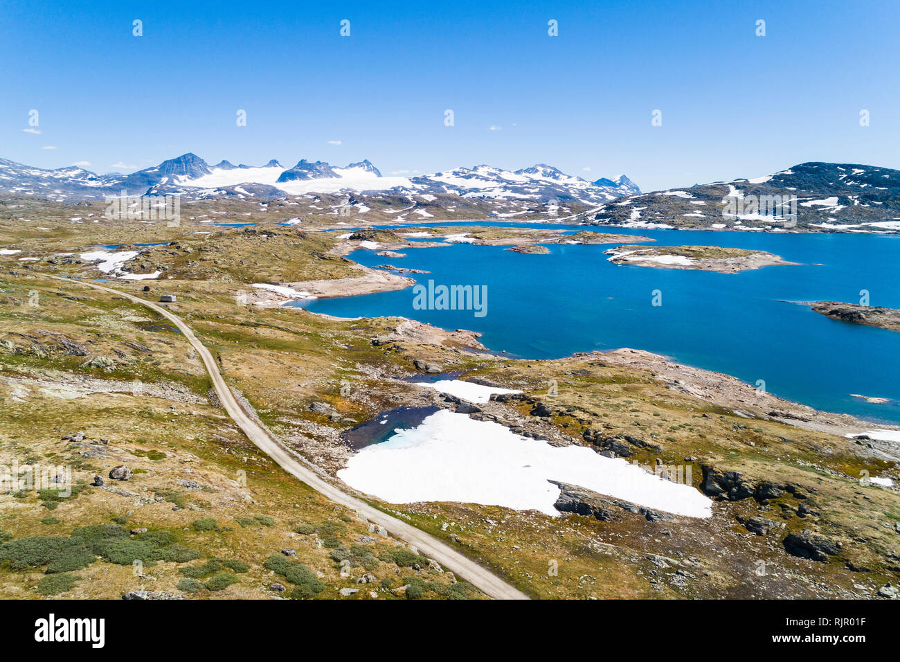 La neve che copre parte del paesaggio dal lago e montagne, vista drone, Sognefjell, Jotunheimen, Norvegia, Europa Foto Stock